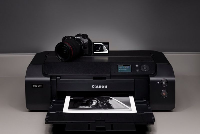 Een Canon imagePROGRAF PRO-300-printer met daarop een Canon-camera, en een print die uit de uitvoerlade komt.