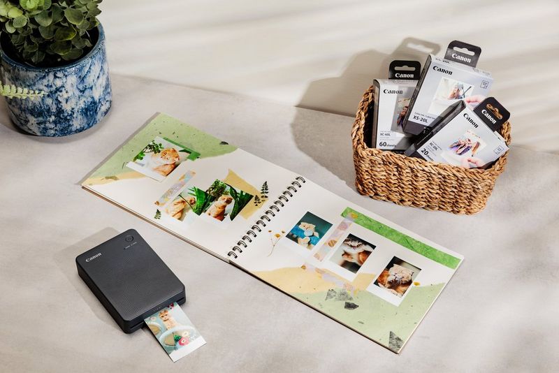 Otvorene stranice spomenara sa slikama mačaka pokraj kompaktnog pisača tvrtke Canon.