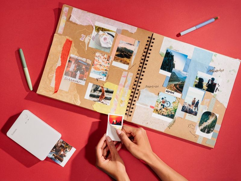 Пользователь снимает подложку со стикера, напечатанного на принтере Canon SELPHY QX20, чтобы приклеить его в альбом.