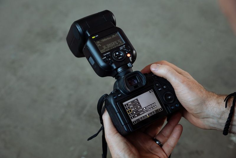 Mano che regola le impostazioni della modalità Gruppo flash (Gr) nella parte posteriore di una fotocamera Canon su cui è montato un flash Canon Speedlite EL-5.