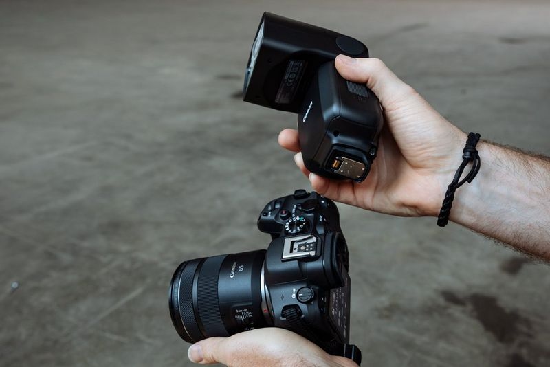 Een paar handen houdt een Canon-camera en een Canon Speedlite EL-5 zo vast dat je de multi-function foot kunt zien.