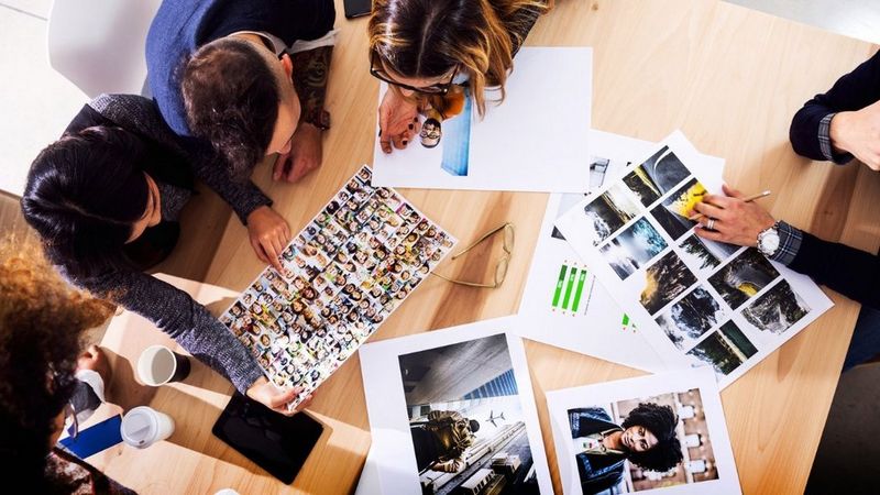 Employees reviewing prints in meeting.
