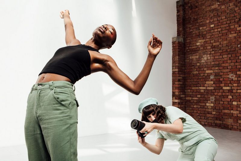 Una modella si piega all'indietro, con le braccia in aria, mentre la fotografa Eliška Sky si china dietro di lei per immortalare la scena.