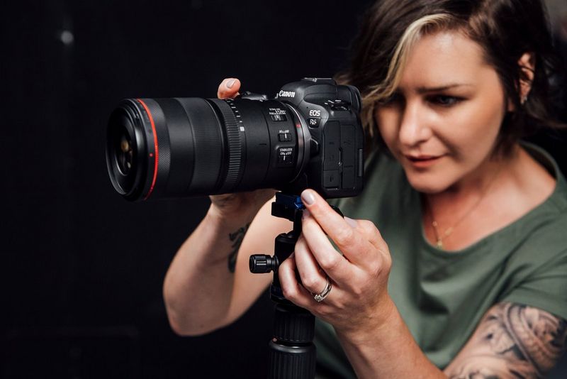 La fotografa Sharon Cosgrove guarda lo schermo della sua fotocamera Canon EOS R6, mentre ne regola l'obiettivo.