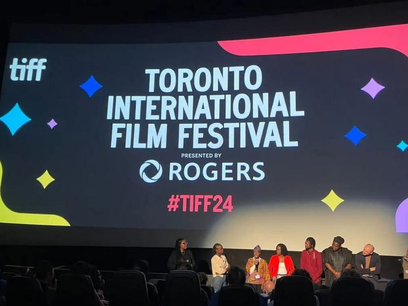 A panel discussion at the Toronto International Film Festival. A panel of six people is seated in front of an audience, appearing to be engaged in a discussion.