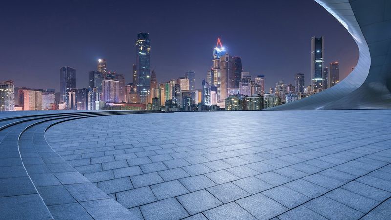 A panorama of a city at night, against a dark blue to light blue gradient background. Overlaid across the city are white connecting lines, to denote how everything is joined together in a smart city. And vertical white lights to symbolise connectivity of technology.