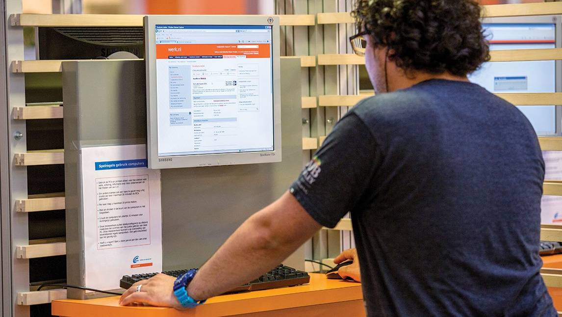 Medewerker van UWV staat achter een computer