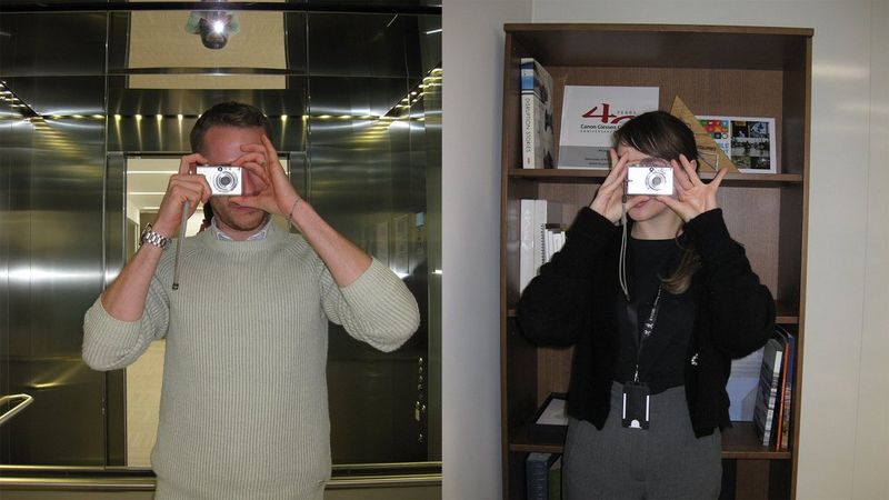 Two images side-by-side of people taking photographs using old Canon digital cameras. They stand holding the cameras in front of their faces, as though taking a photograph of the viewer.