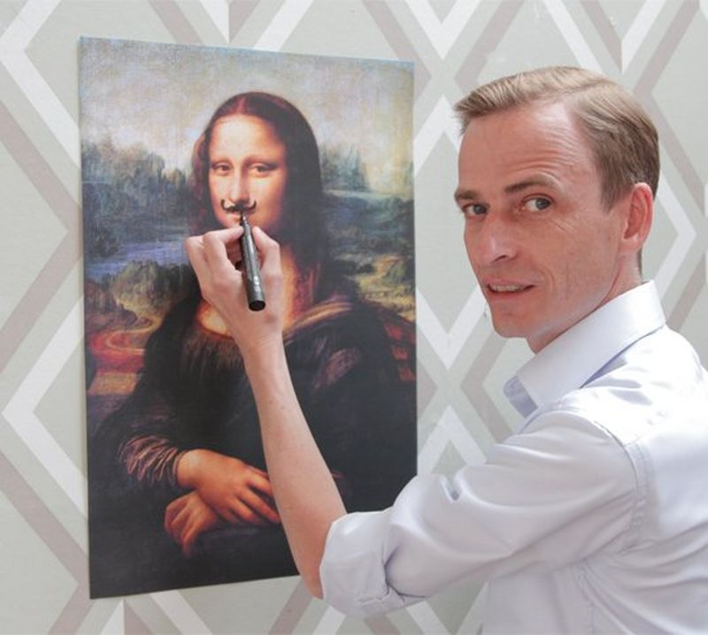 A man scribbles a moustache onto the Mona Lisa