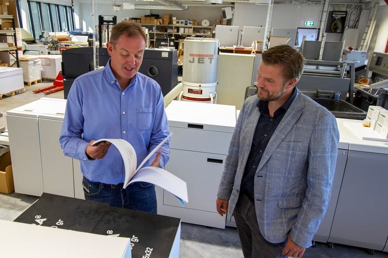 Dag Brekke-Rasmussen og Jon Larsen blar i en bok 