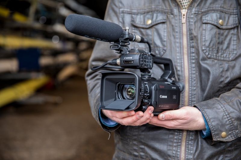 Мужчина держит на ладони видеокамеру Canon XF405.