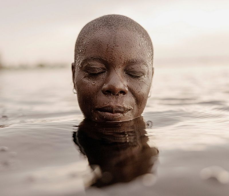 The face of a swimmer, Yvette Tetteh, emerges from water with her eyes closed. 