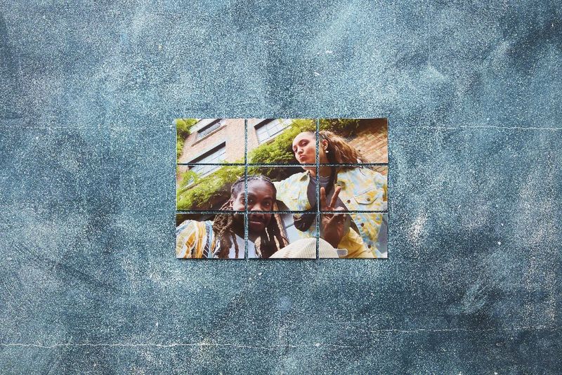 Une image d'un jeune homme et d'une femme qui sourient composée d'une série d'images plus petites sur un mur bleu-gris.