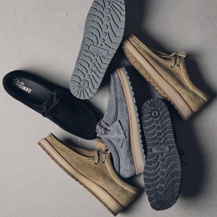 Clarks Originals Wallabee Scout shoes scattered on a grey cement floor.