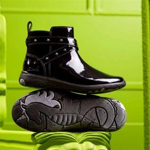 Black children's school boot against a bright green background