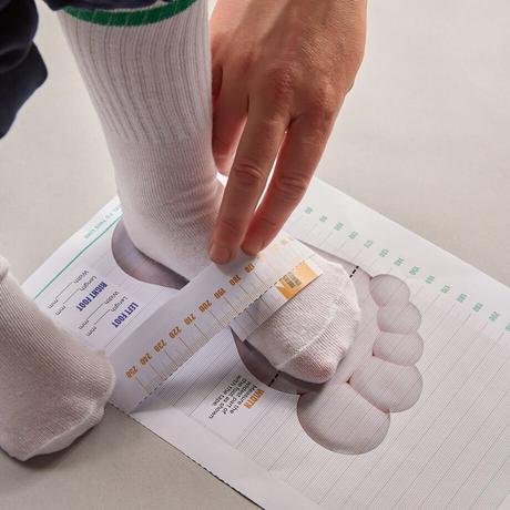 Child's foot being measured using a paper tape measure