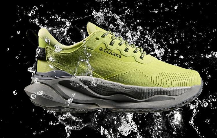 Lime green Clarks Pace trainer with a thick cushioned sole against a black background with water splashes