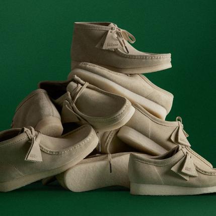 A pile of wallabees in front of a green background | Shop Wallabees