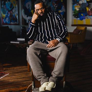 Raekwon sat facing the camera in wallabees