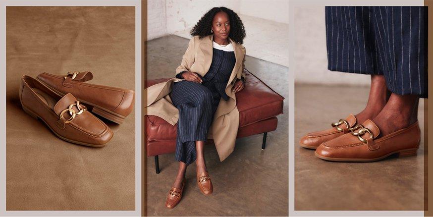 Young woman sitting on an ottoman wearing business attire featuring Clarks’ tan leather Sarafyna Iris Loafers with gold hardware