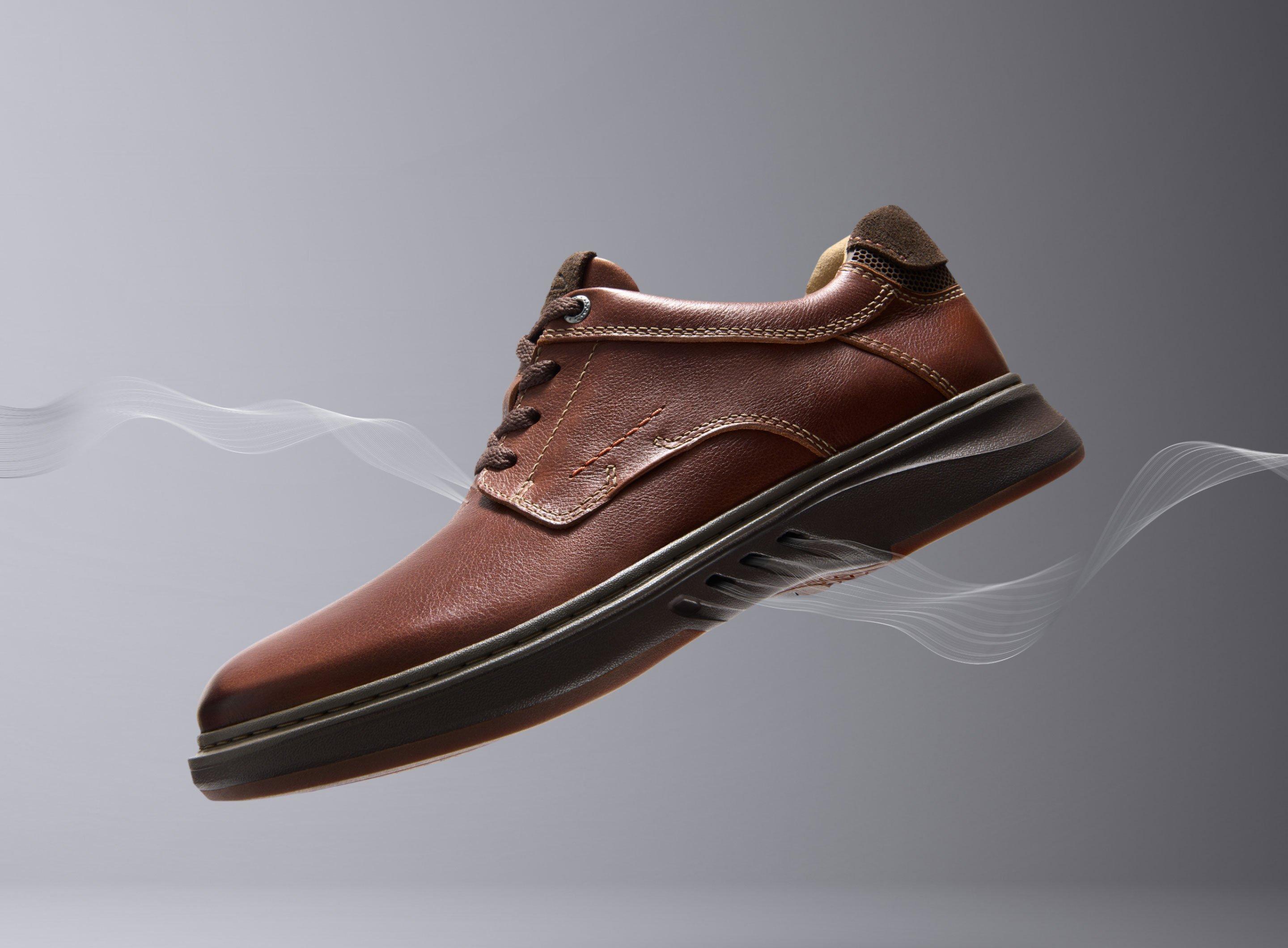 Clarks Unstructured smart-casual brown leather shoe Un Briley Pace floats above ground with a graphic of air flowing through the shoe. Clarks Unstructured logo appears to the left of the shoe.