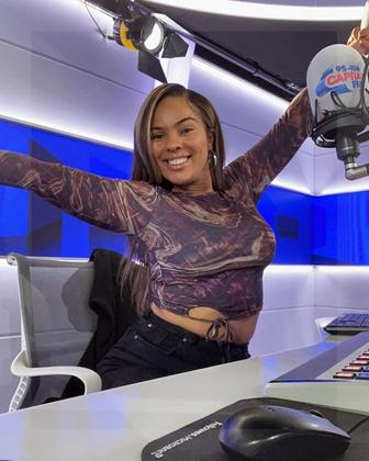 Kamilla cheering while sitting on a chair at a radio studio