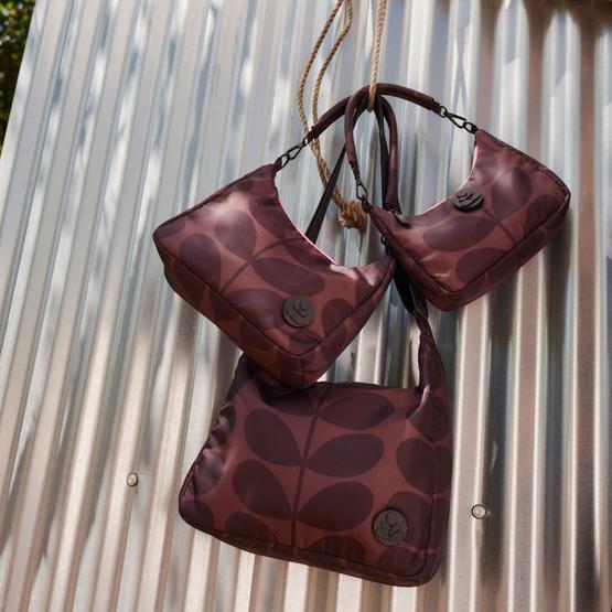 Burgundy Orla Kiely patterned bags hanging against corrugated metal