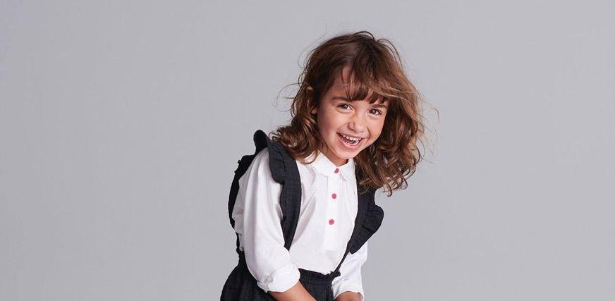 Laughing school girl wearing a white shirt with and black pinafore dress