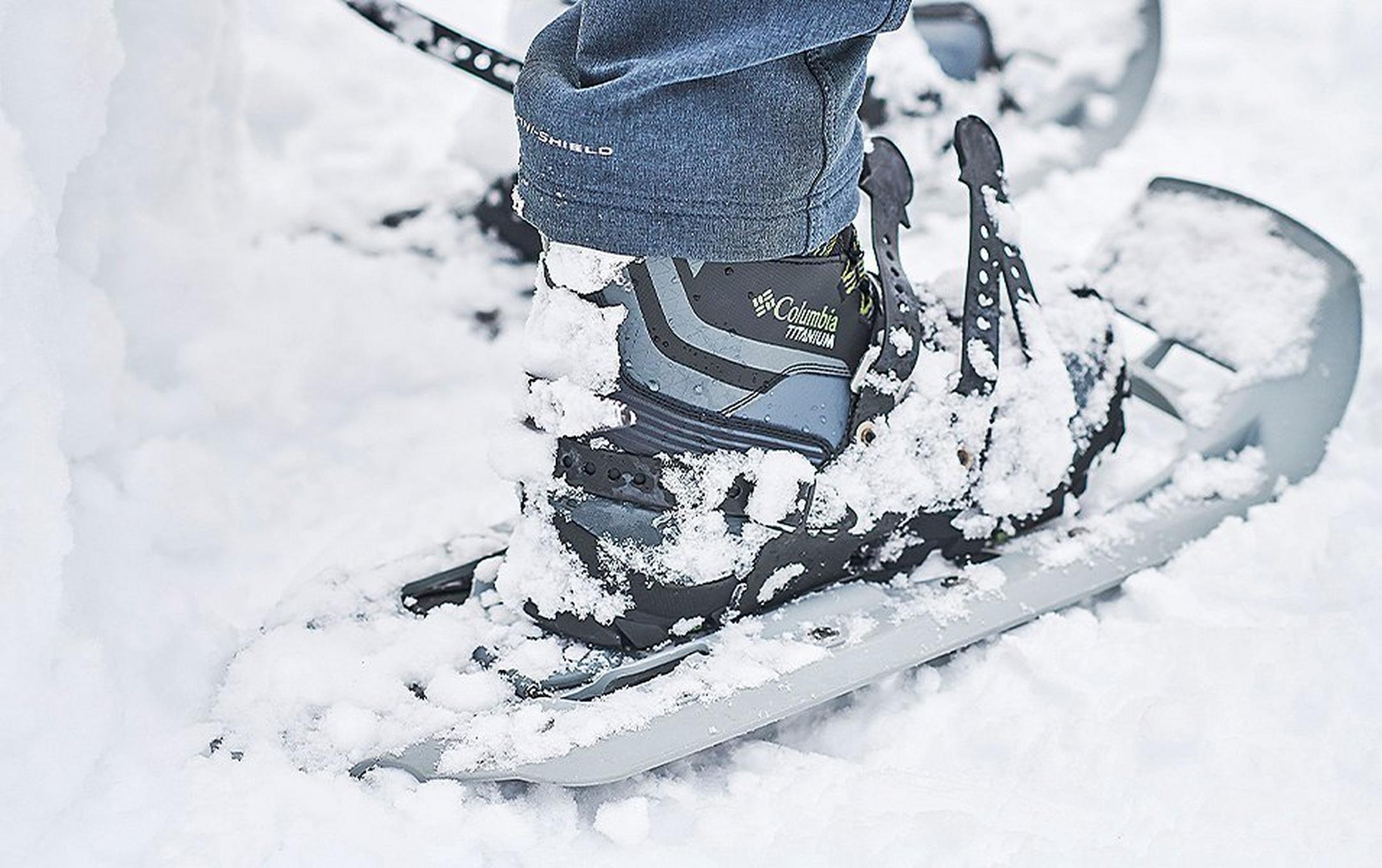 Close up of Titanium Columbia boots and snowshoes in snow.