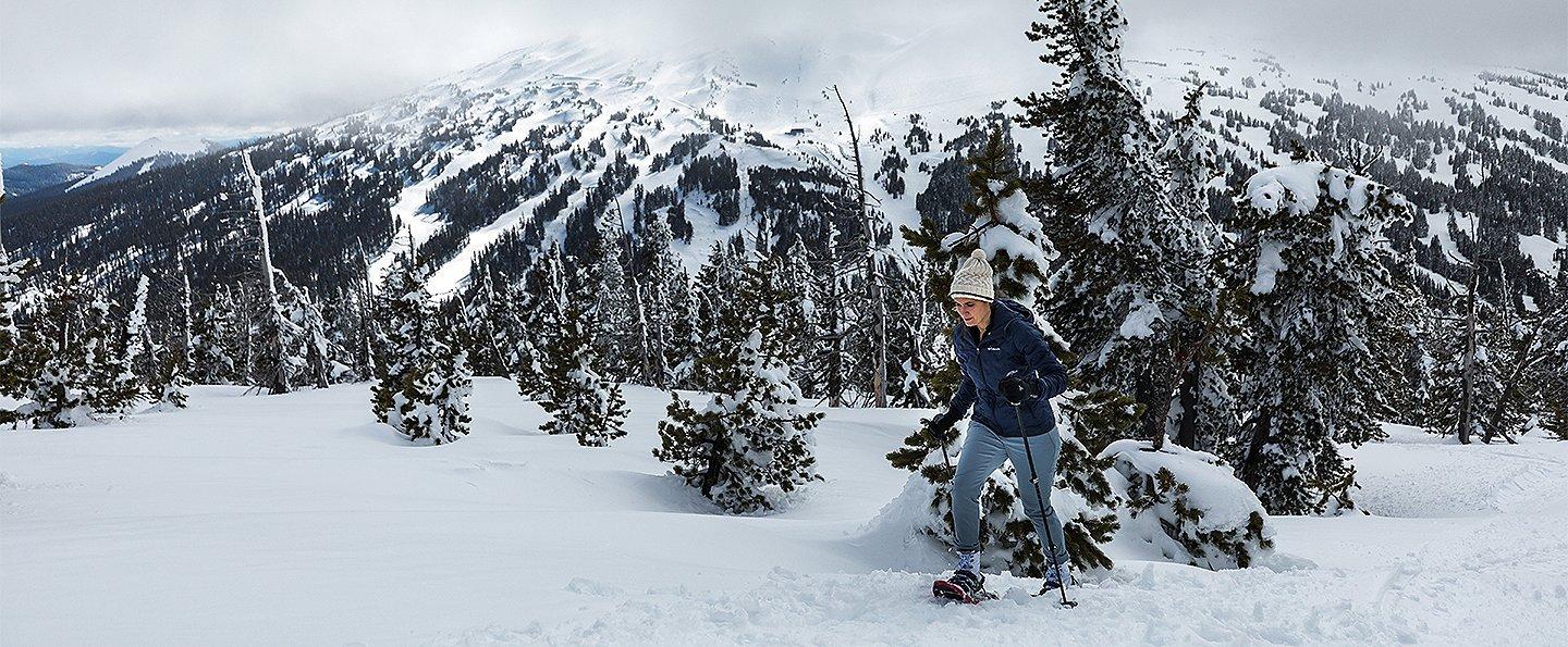 Woman snowshoeing in a winter mountain scene.