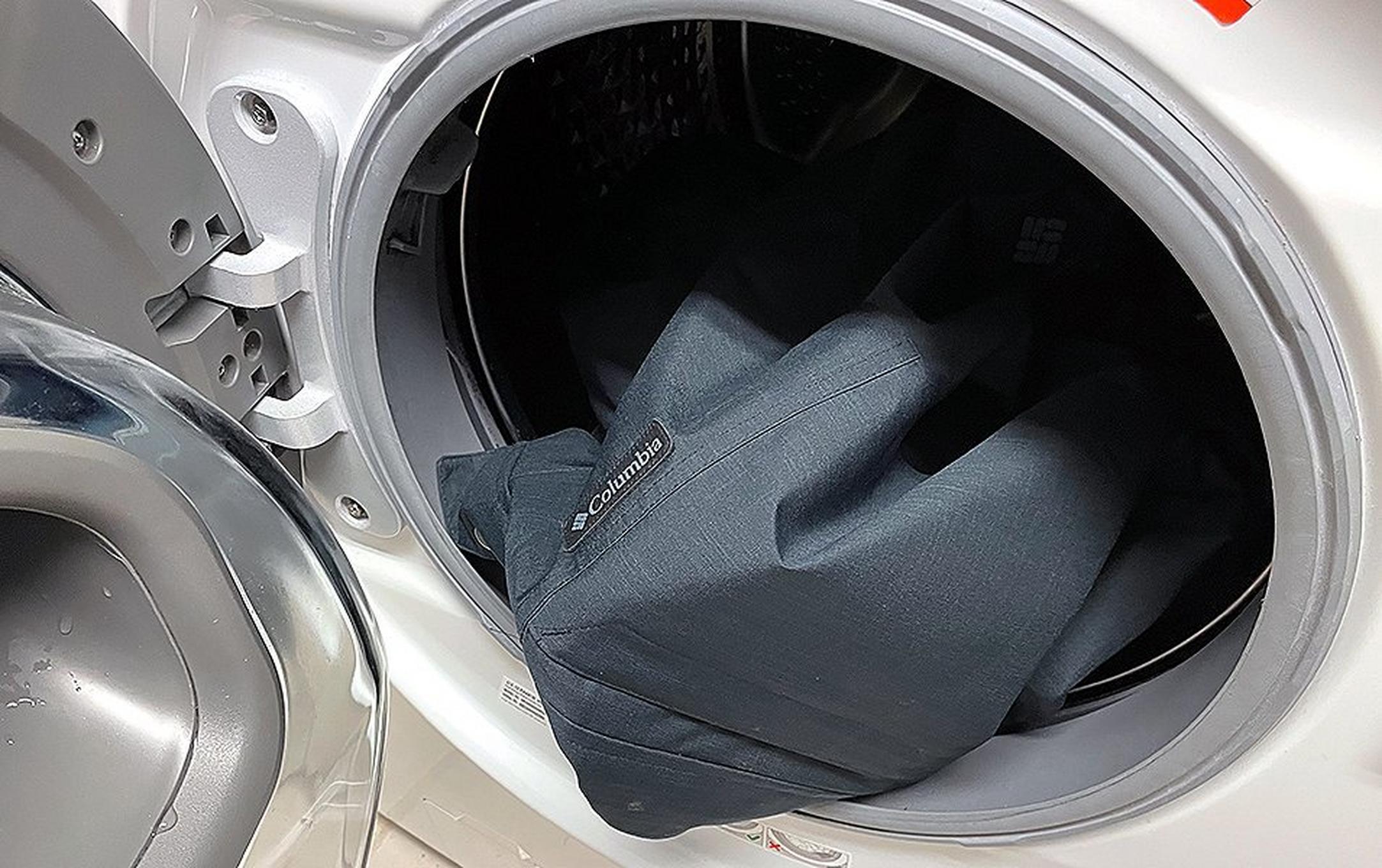 A ski jacket is pictured in a dryer with the door open.