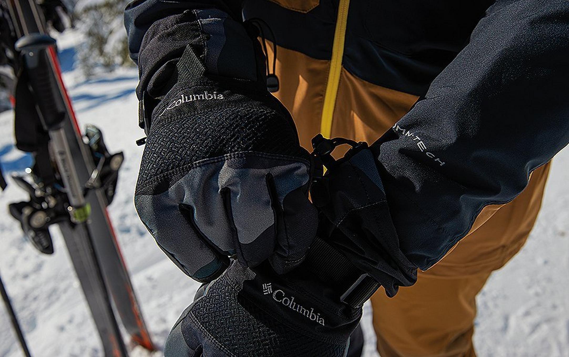 A skier adjusts his winter gloves on the mountain.