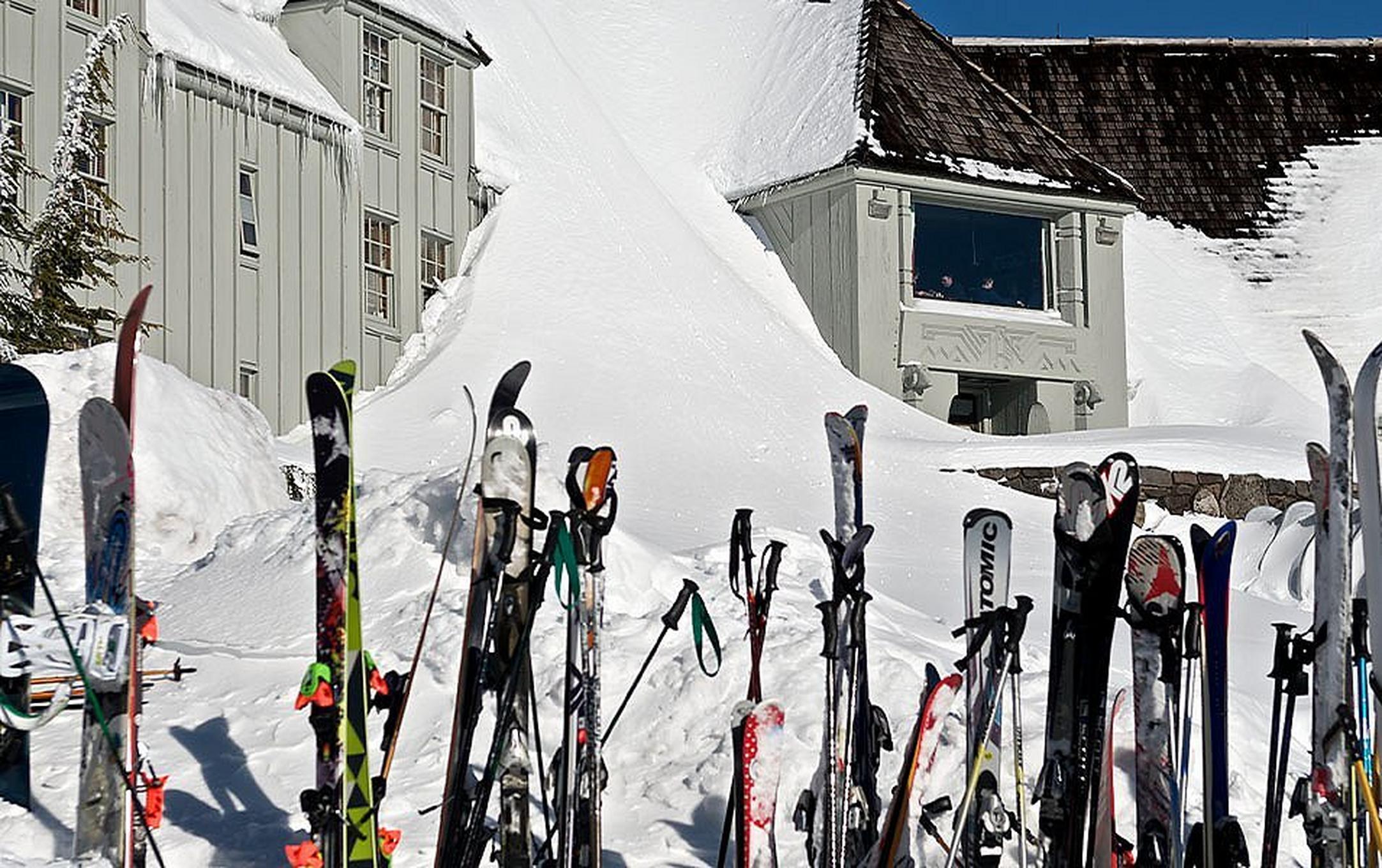 A line of skis sit in the sun on a rack outside Timberline Lodge.