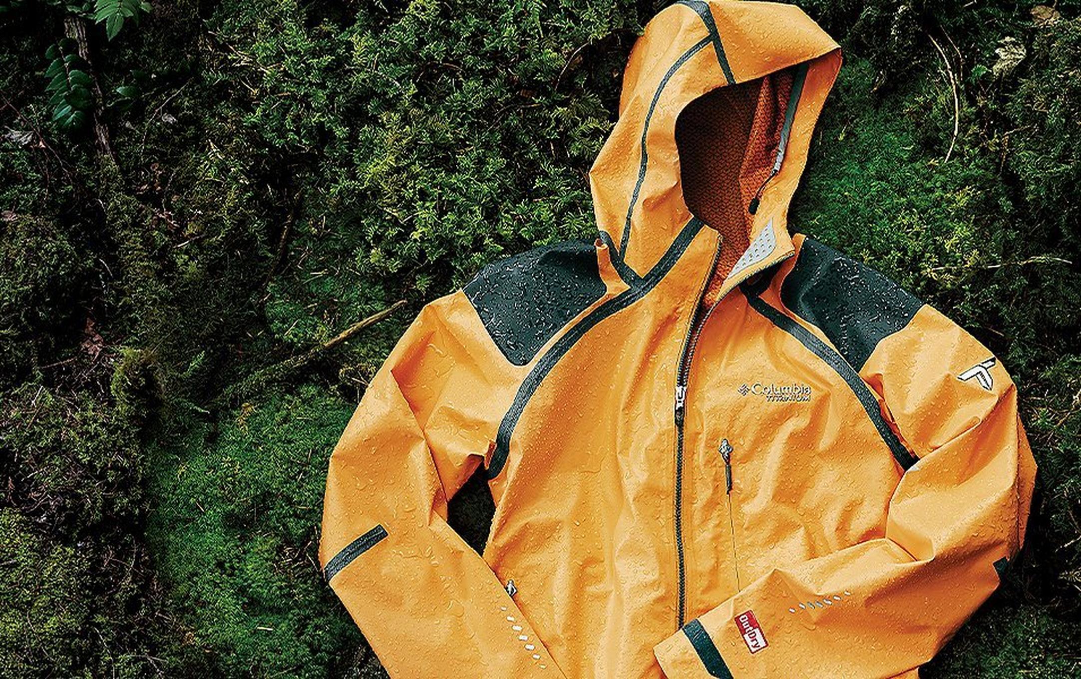 An orange and black color blocked Outdry Extreme jacket laying on a mossy background.