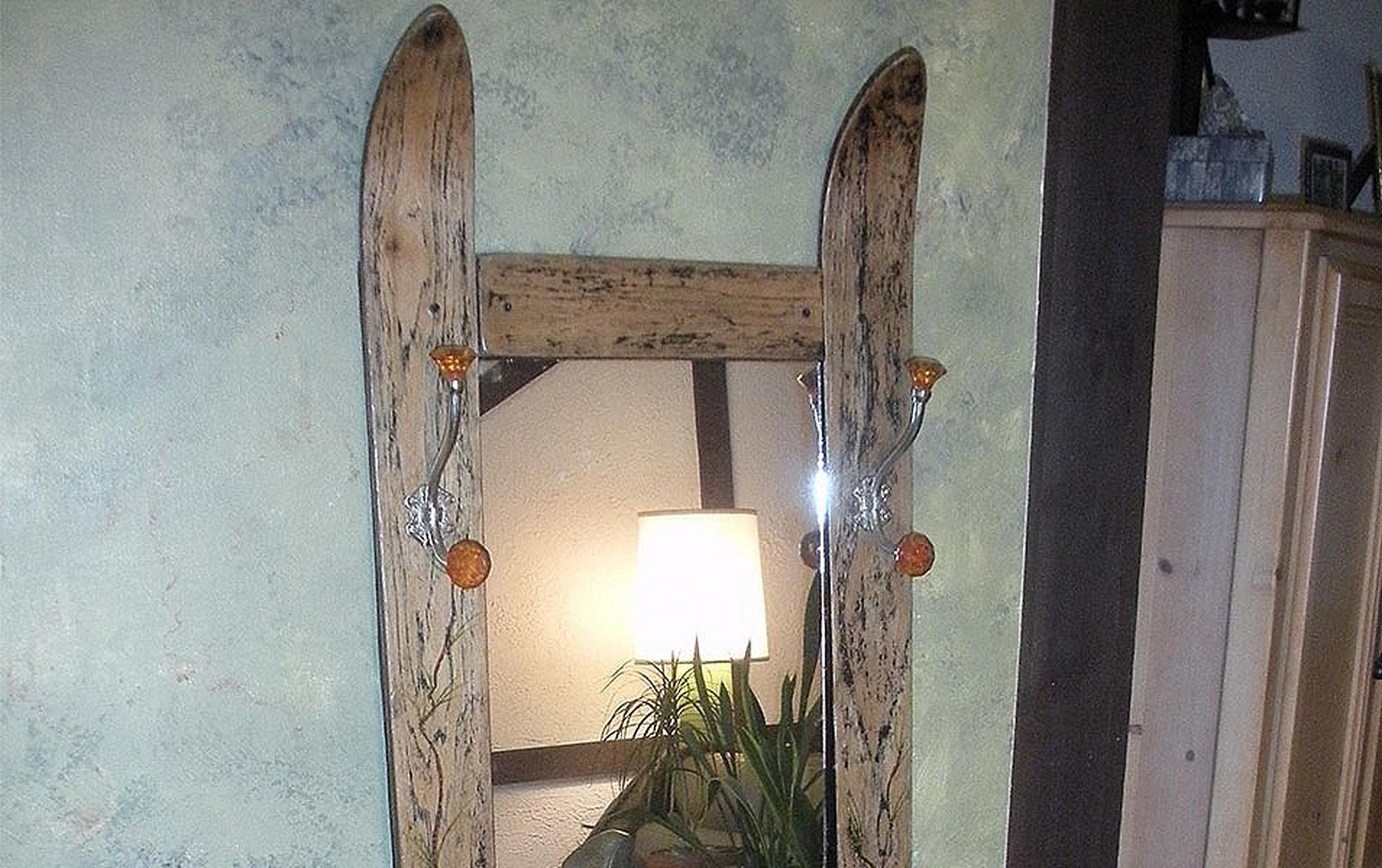A mirror sits on a wall made with old skis as the frame.