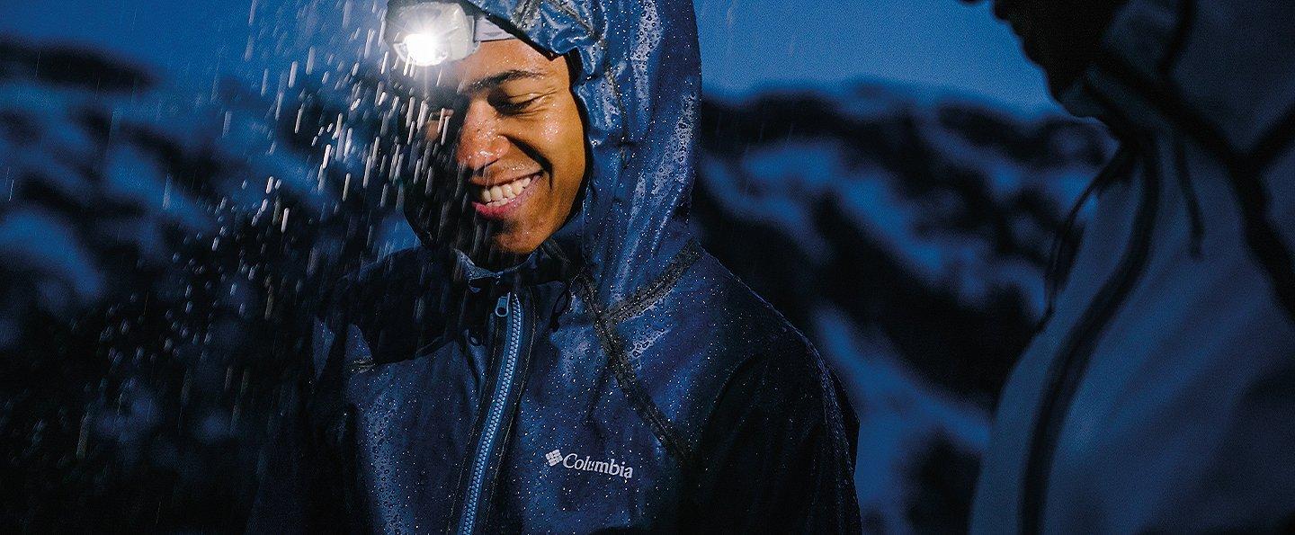 Close up of man with headlamp on a rainy night.
