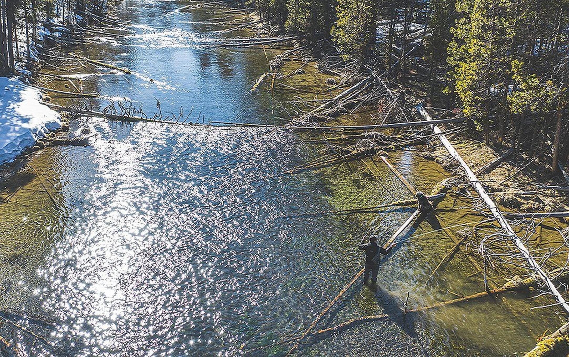 An aerial photo of a man in a river fly fishing from a distance.
