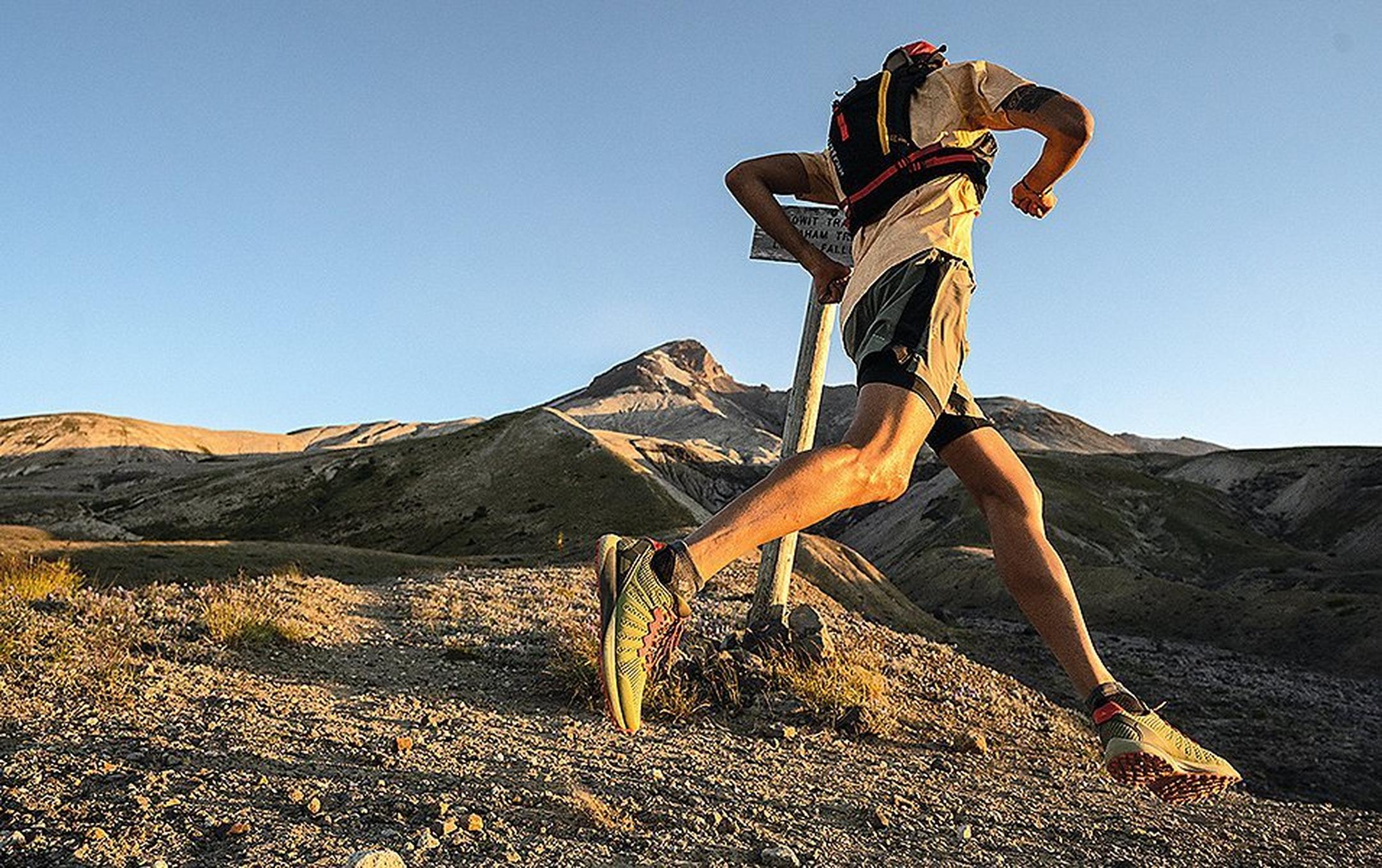 Man running along rocky trail at sunset.