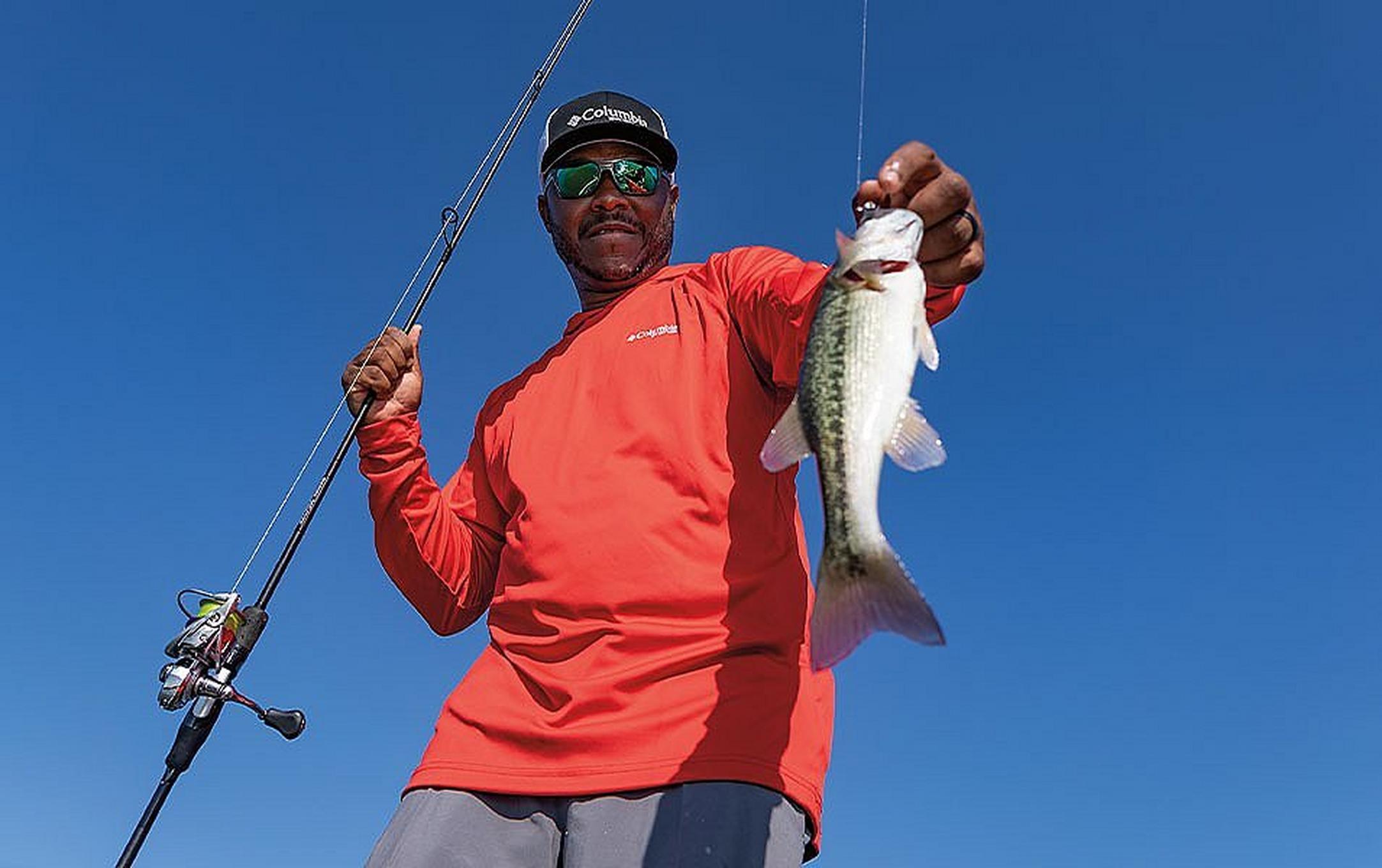 Pro angler Mark Daniels Jr. holds a fish for the camera and smiles.