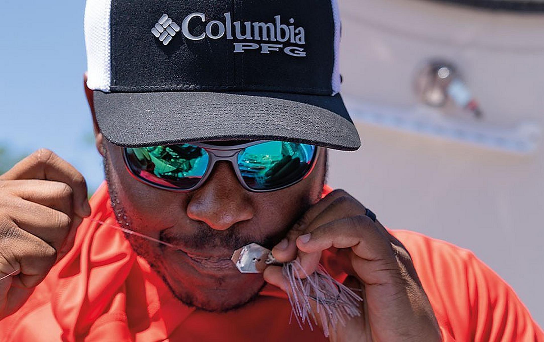 Pro angler Mark Daniels Jr. ties a fishing knot with a piece of bait.