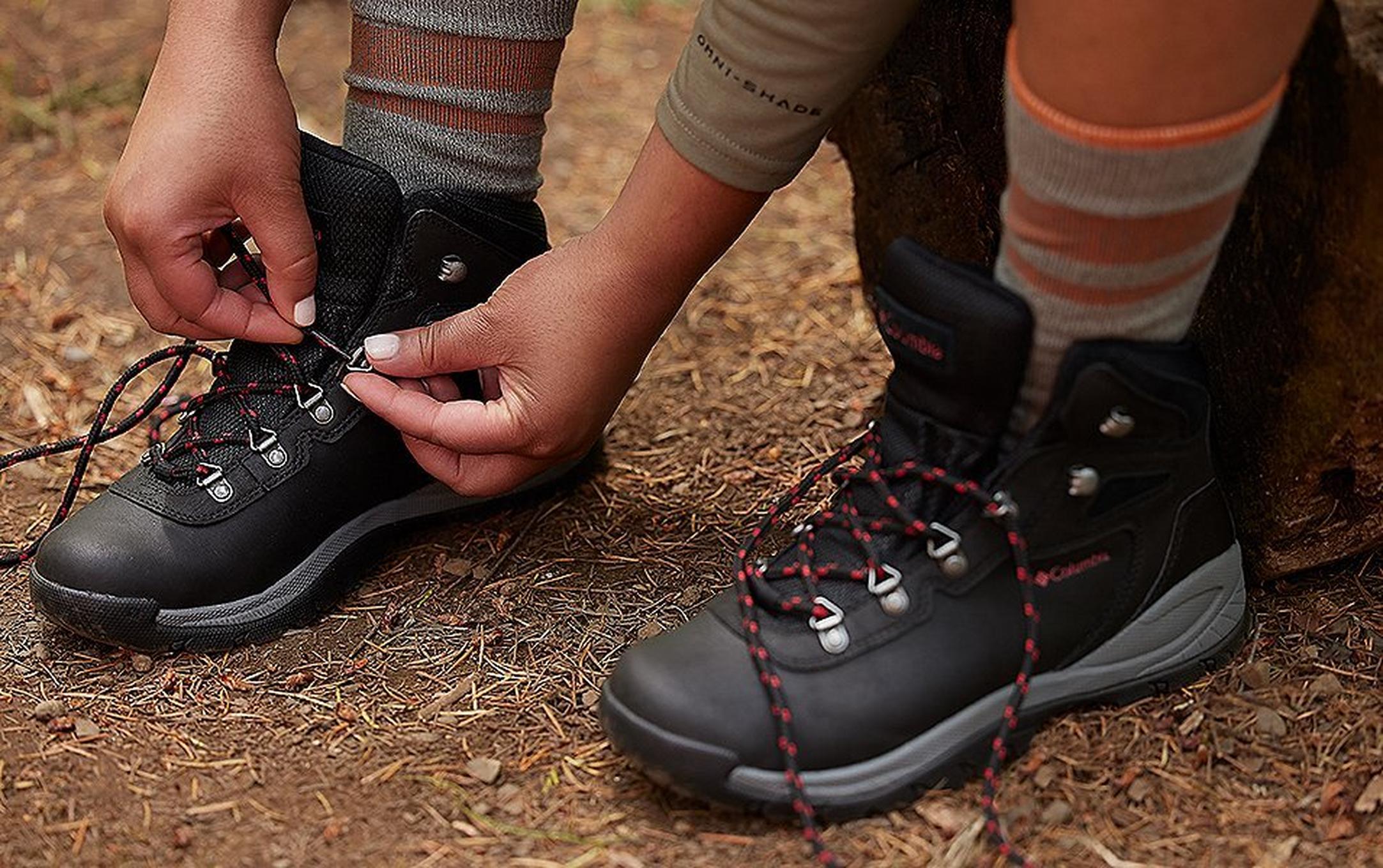 Hiker lacing Columbia Sportswear hiking boots.