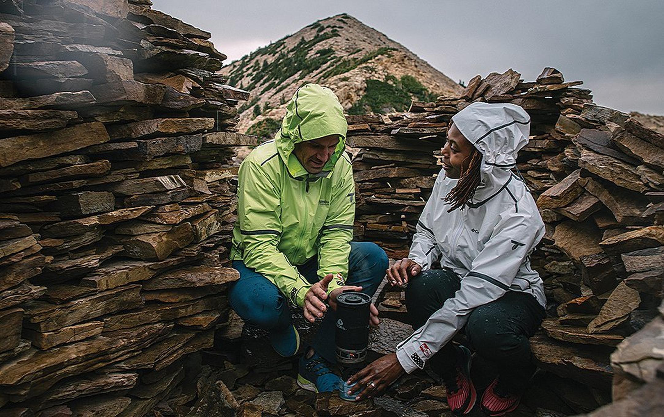 Two people crouching near a camp stove.