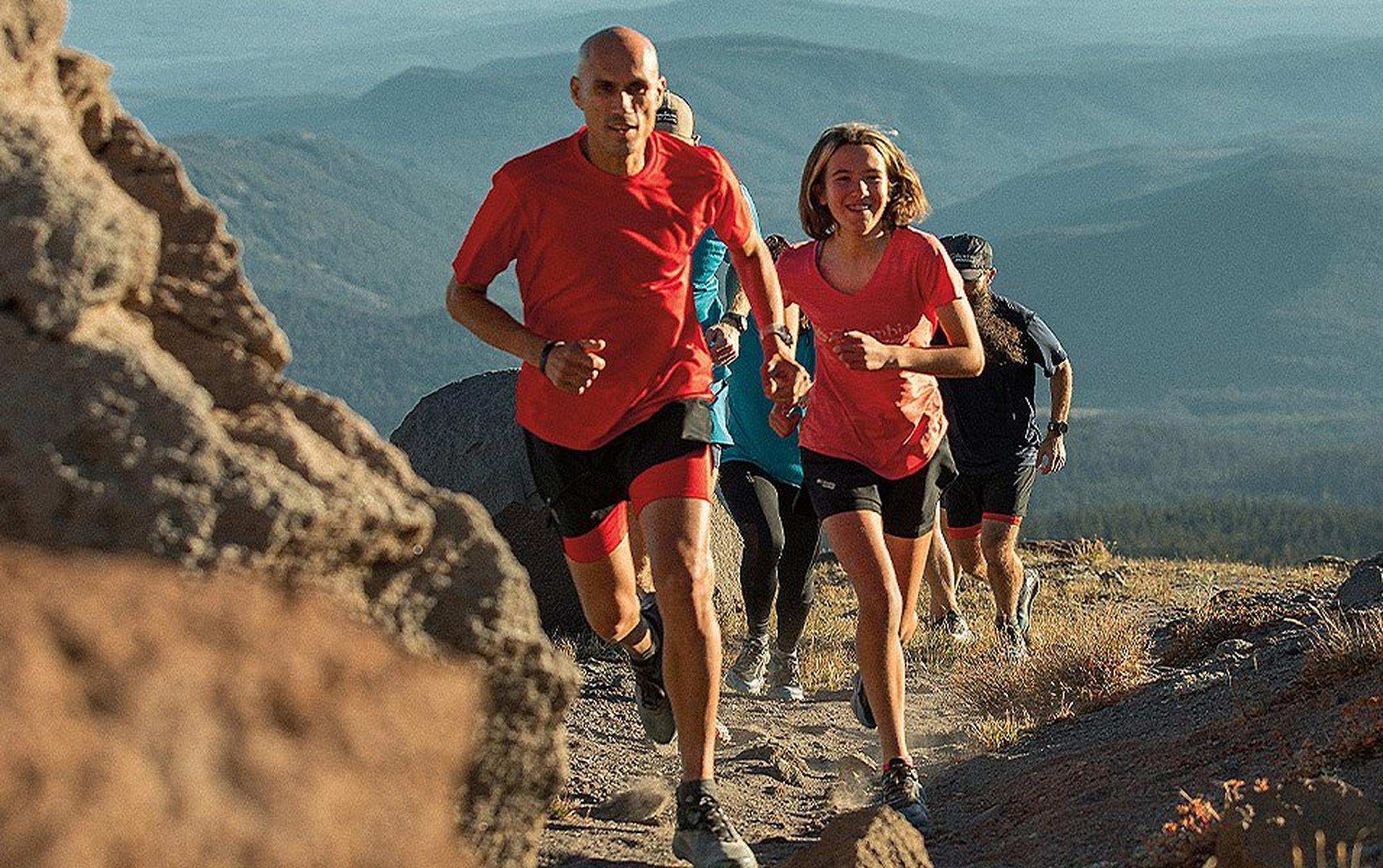 Several people of different ages run up a dirt trail.