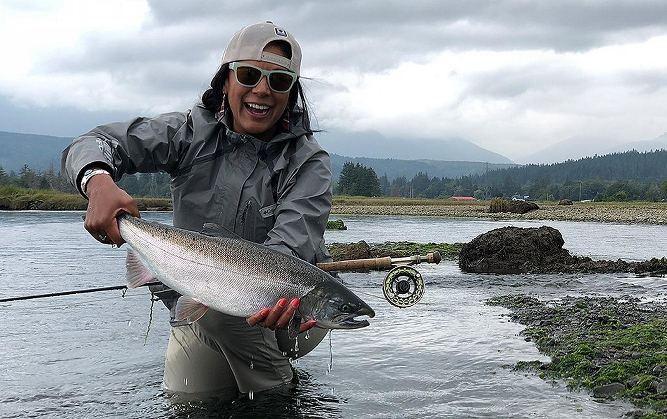 Ruth Sims holding a fish in a river.