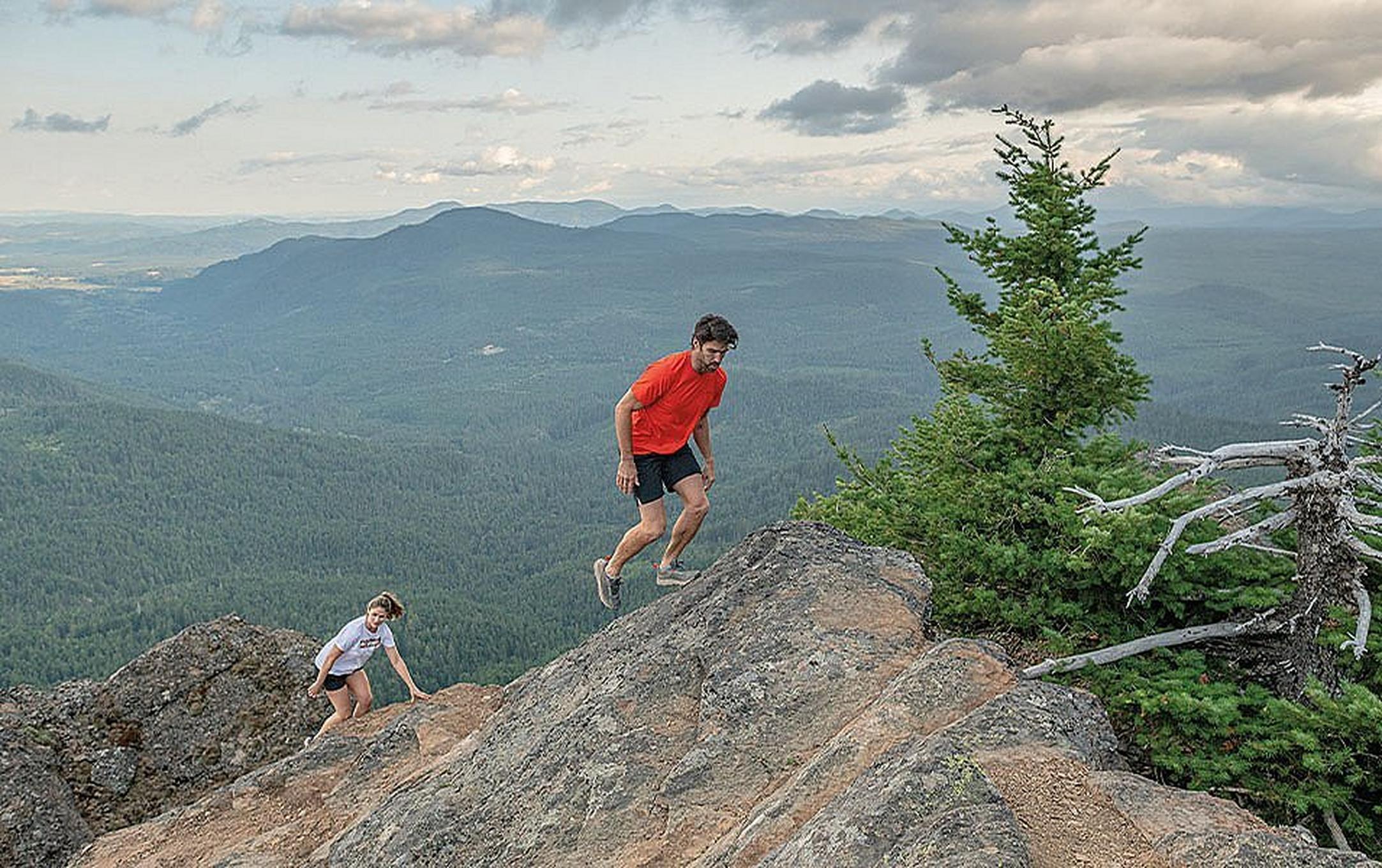 A couple of hikers climbing up a rocky ridge.