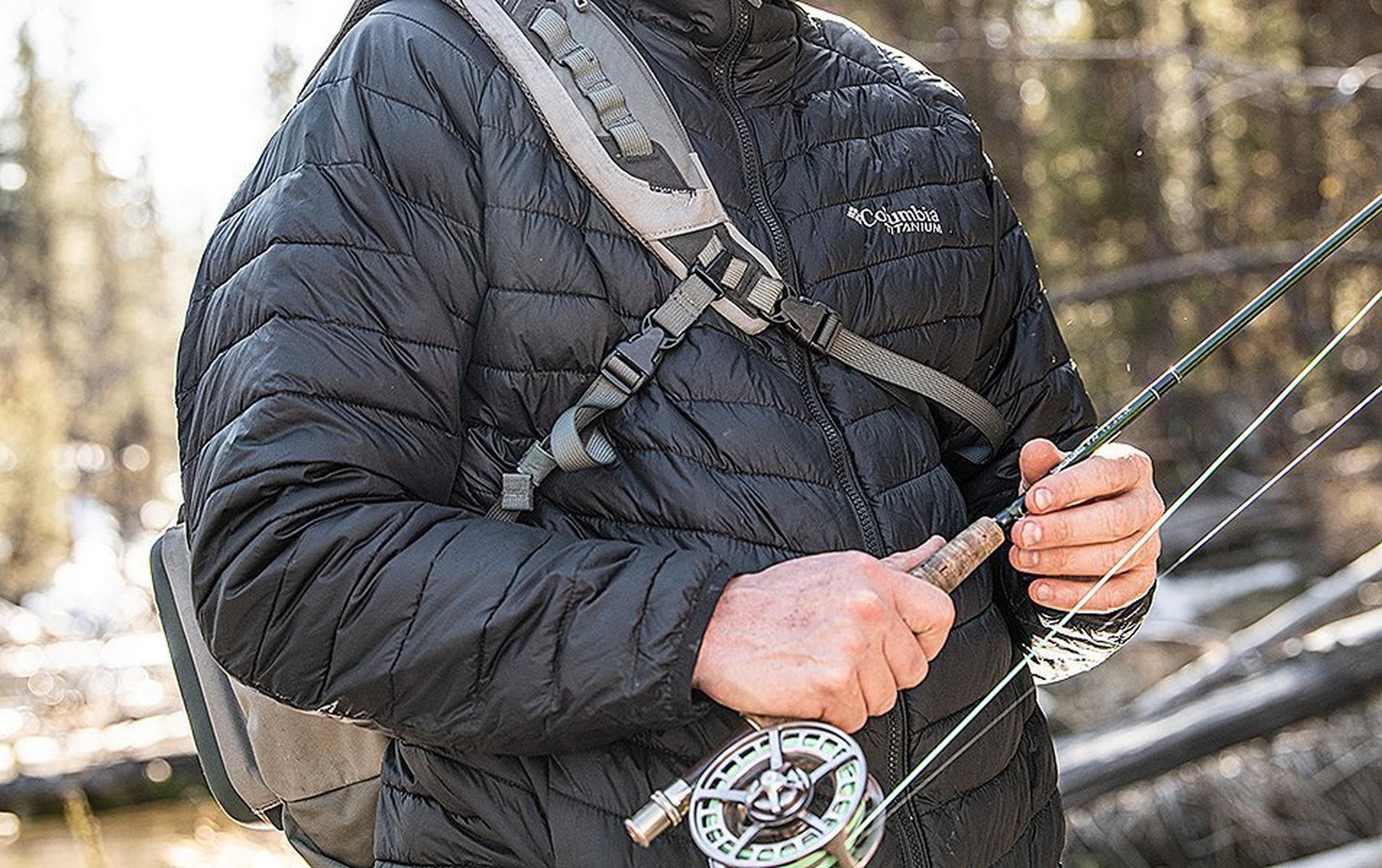 Close-up shot of a fisherman’s hands holding a fly fishing rod.