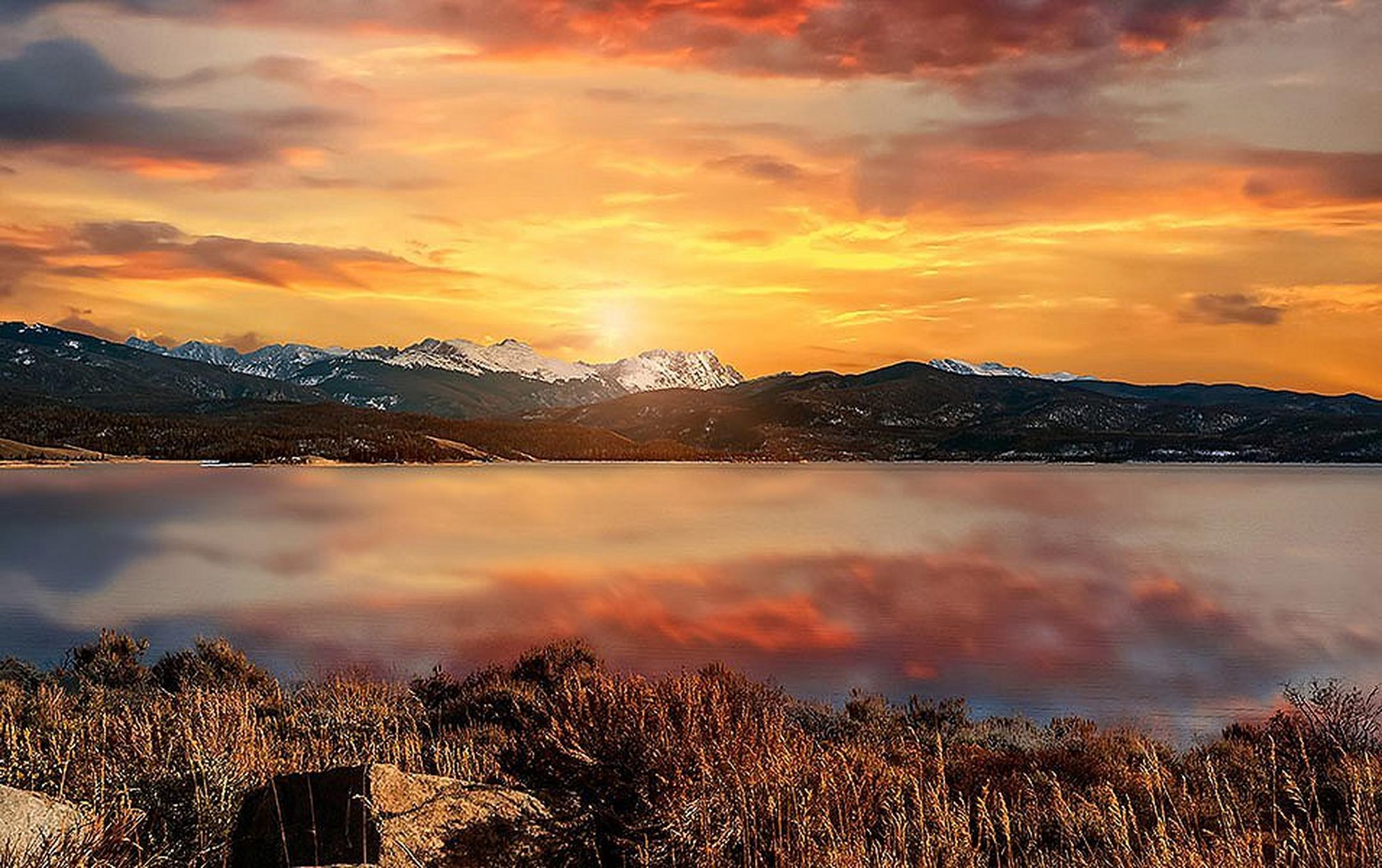 The orange sky is reflected in a beautiful lake at Rocky Mountain National Park in Colorado.