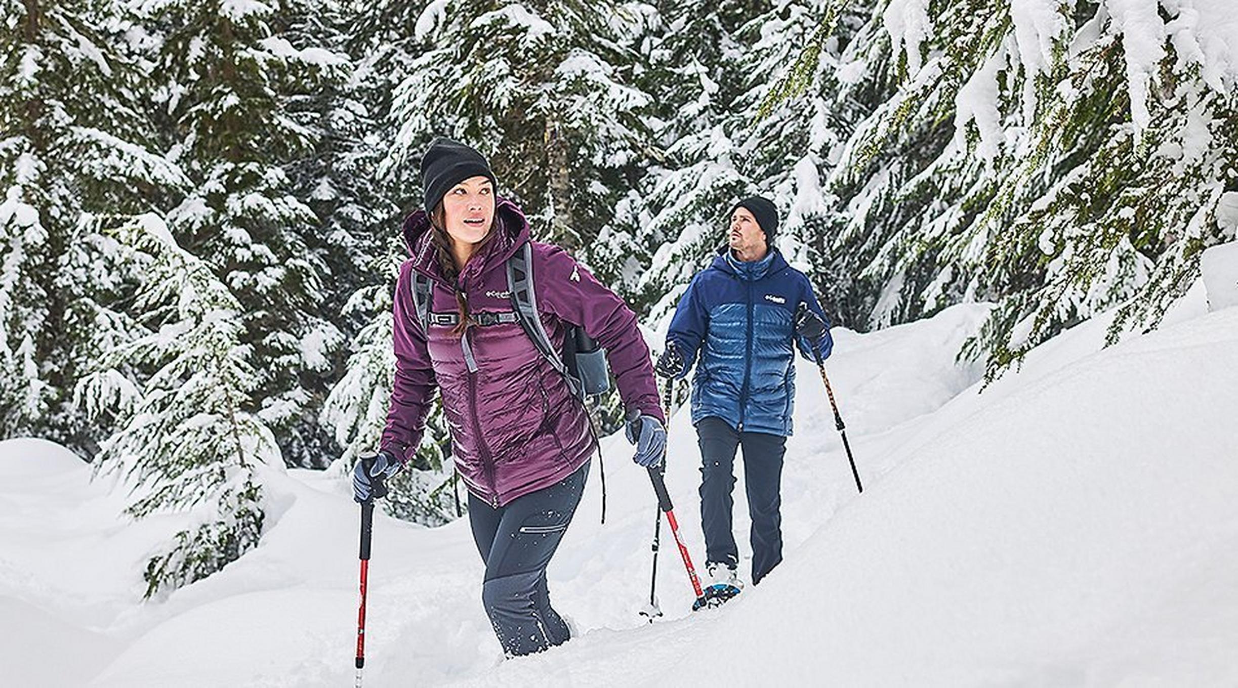 Man and woman snowshoeing in the forest.