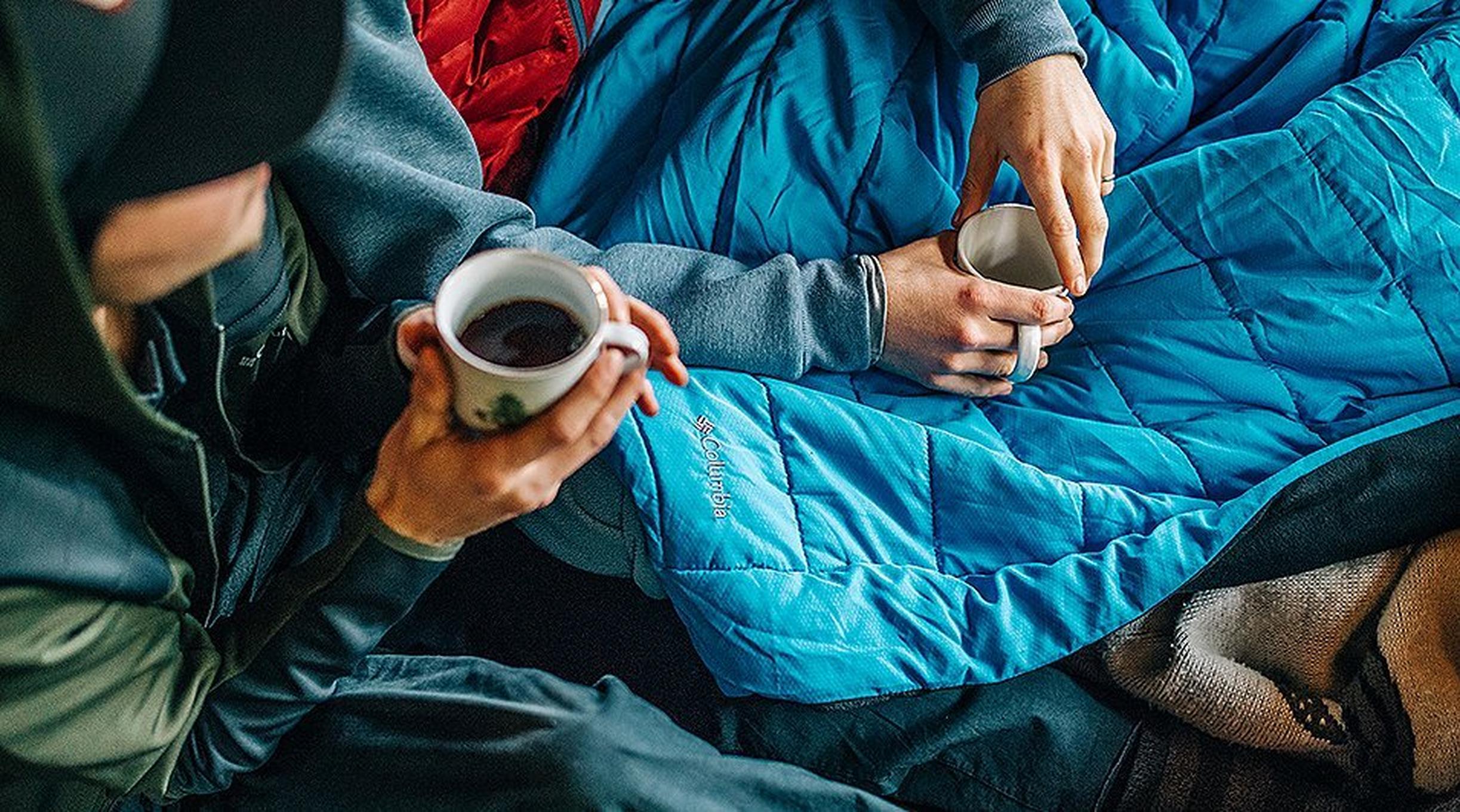 Friends drinking from coffee mugs in blankets.
