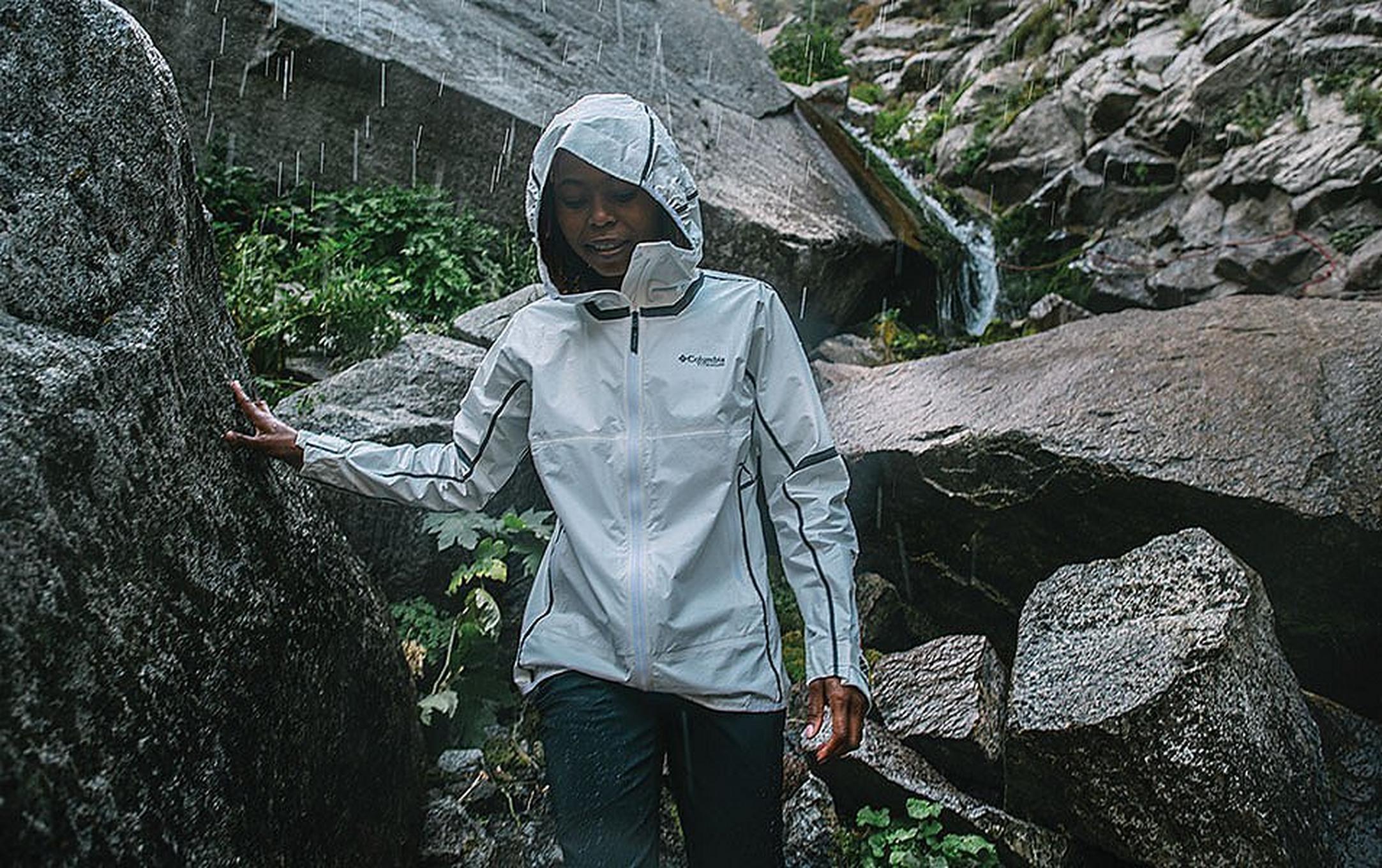Woman climbing down a rocky slope in the rain.